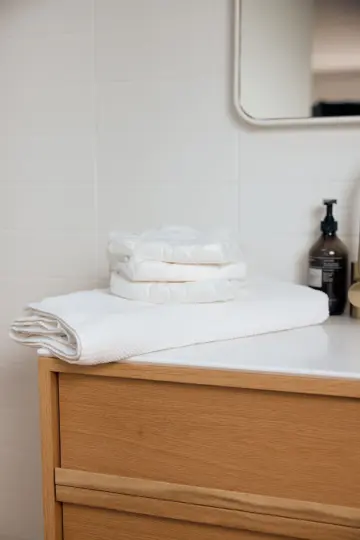 Three folded Svelte pull-ups on a white towel beside a timber bathroom vanity.