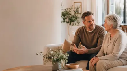 An adult son having a calm conversation with his older mother in a comfortable home setting.