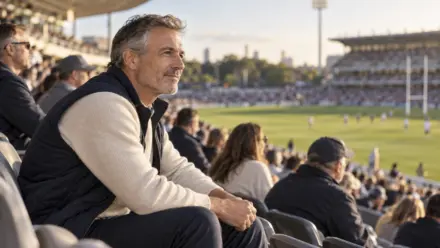 A man in his fifties watching a rugby match from the grandstand