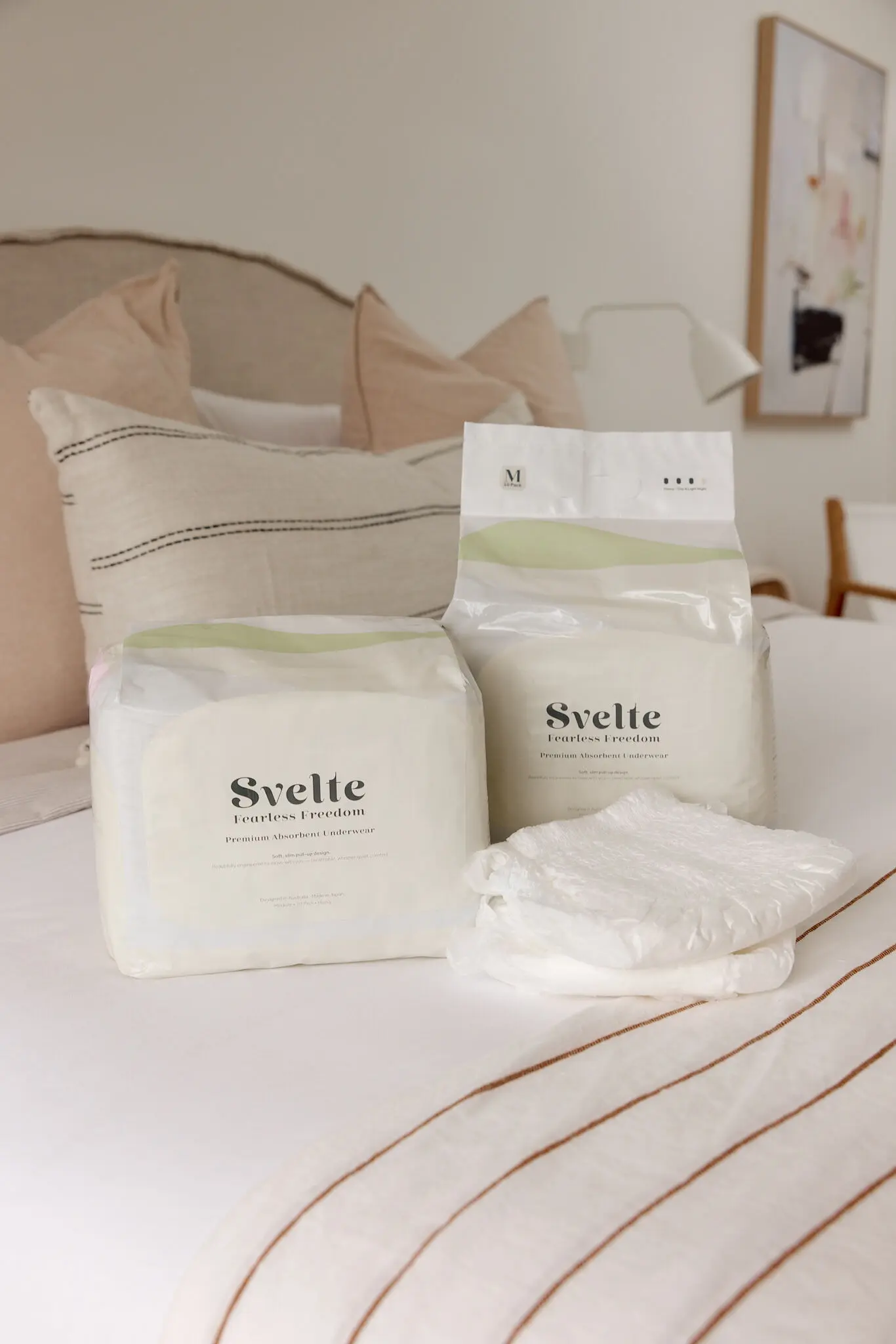 Svelte pull-up continence underwear packs with a folded pull-up on a soft neutral bed.