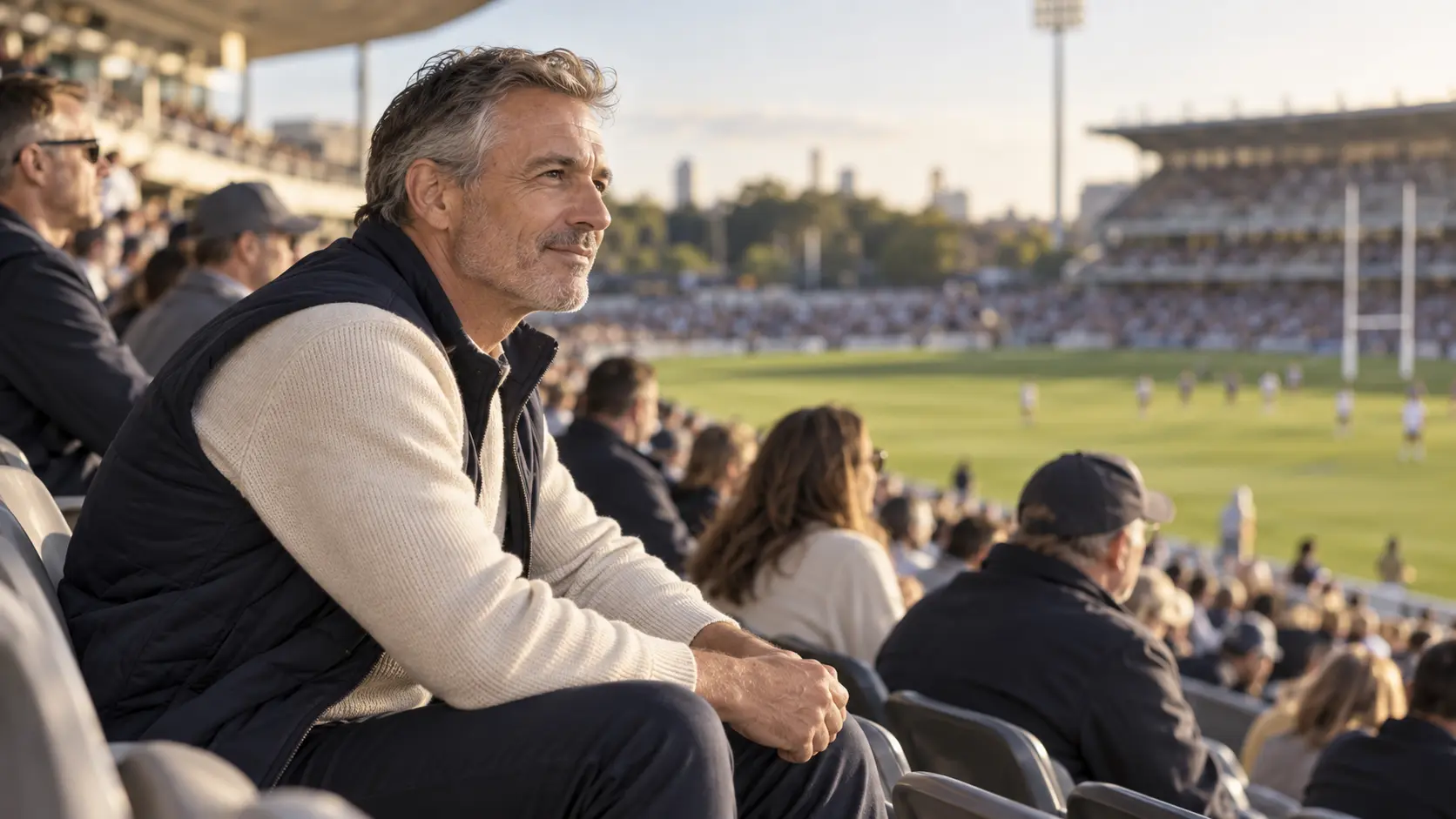 A man in his fifties watching a rugby match from the grandstand