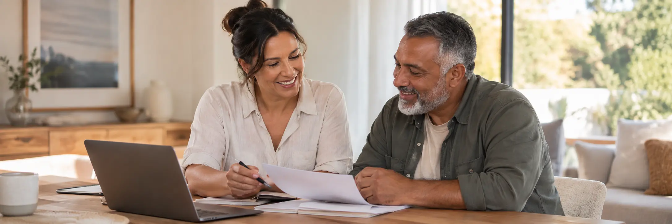 Plan manager and adult participant reviewing paperwork together at a table with a laptop.